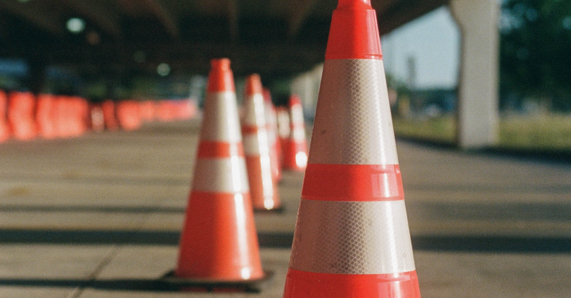 A few orang hazard cones lined up in the middle of a road.