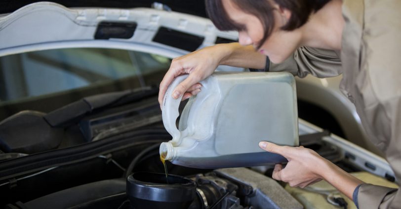 A woman pouring engine oil into the engine.
