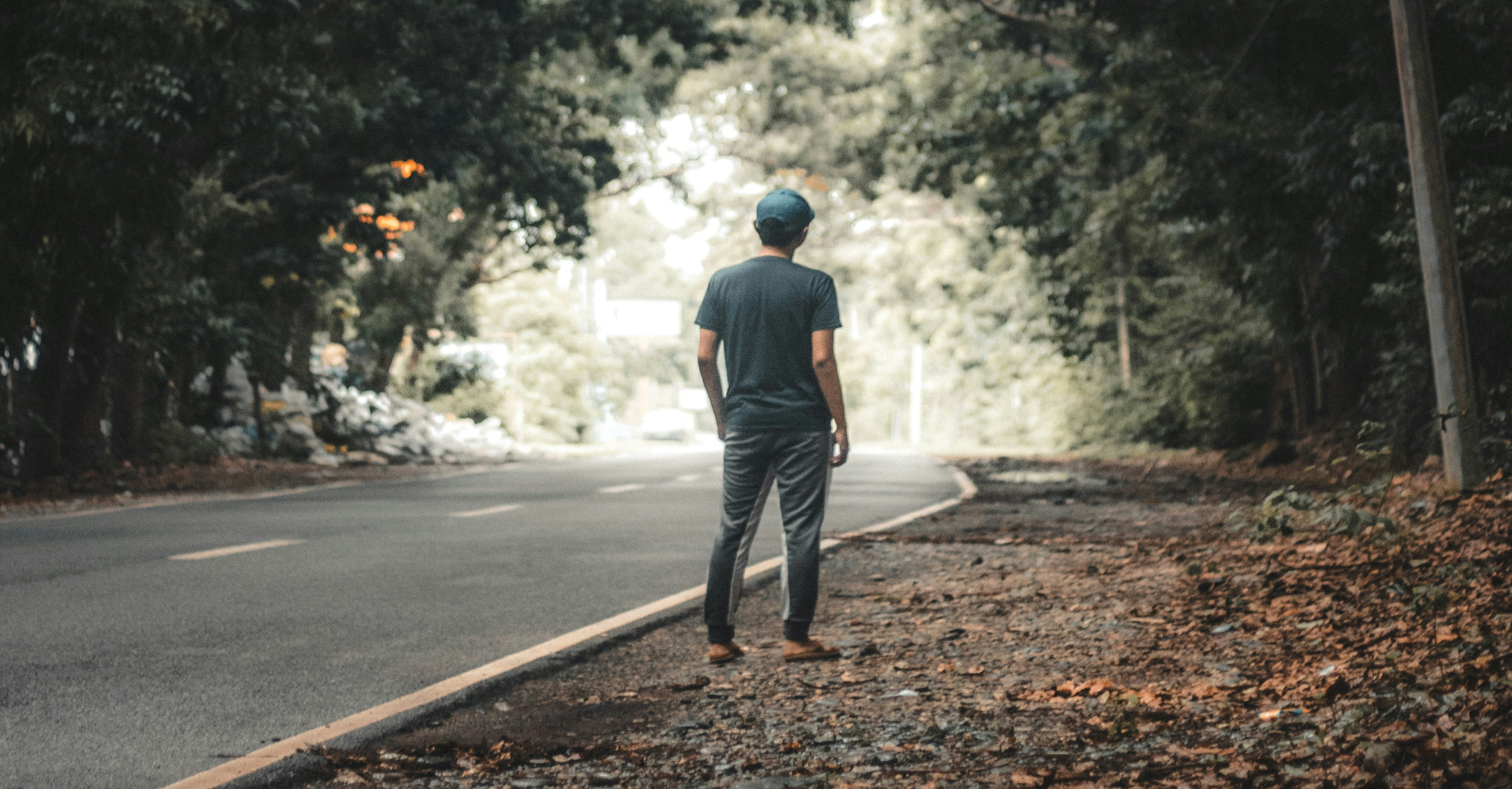 A Man Walking On An Empty Road In Daytime. 